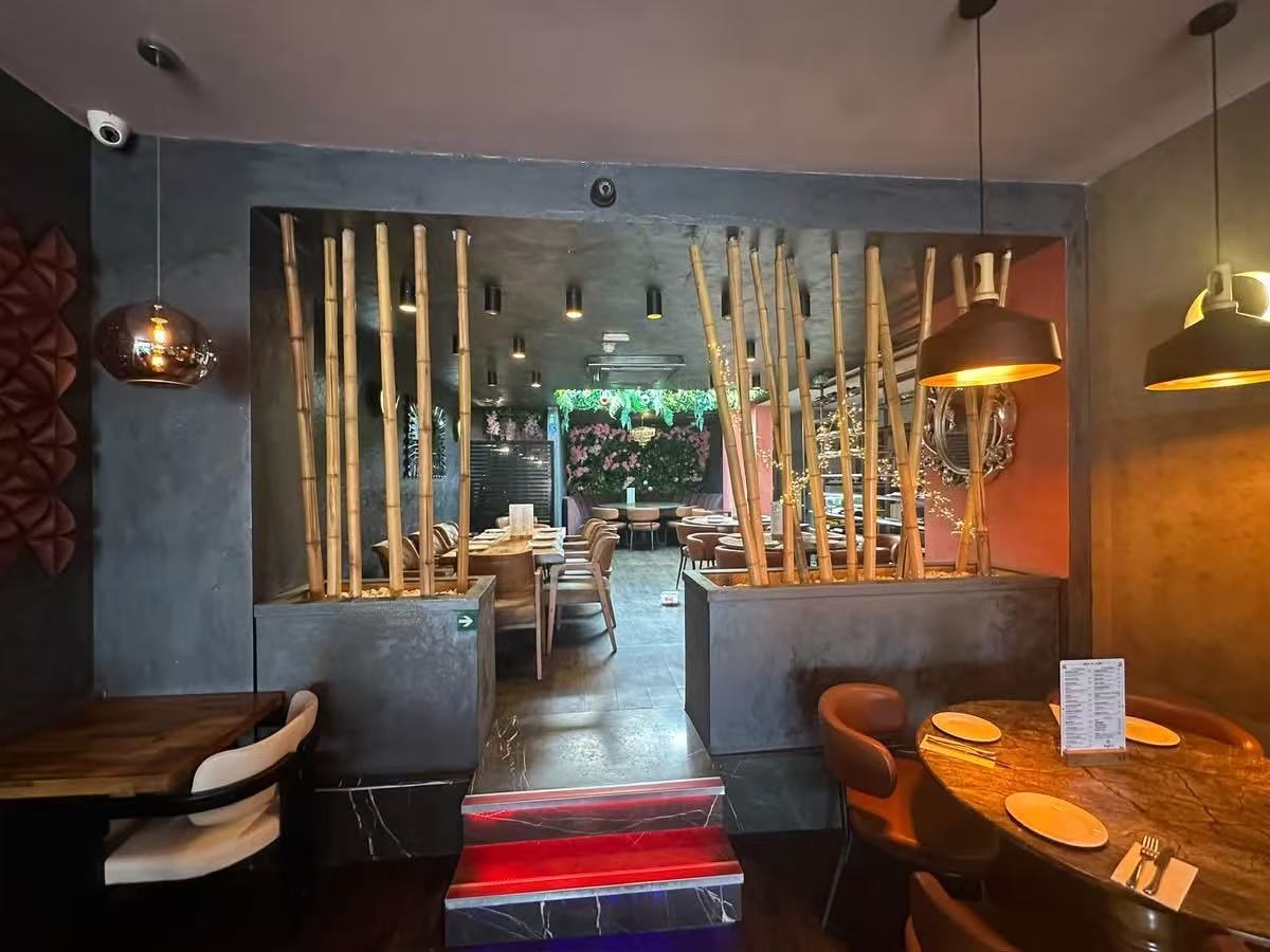 Restaurant transition area with timber screens, steps, dining tables and warm pendant lighting