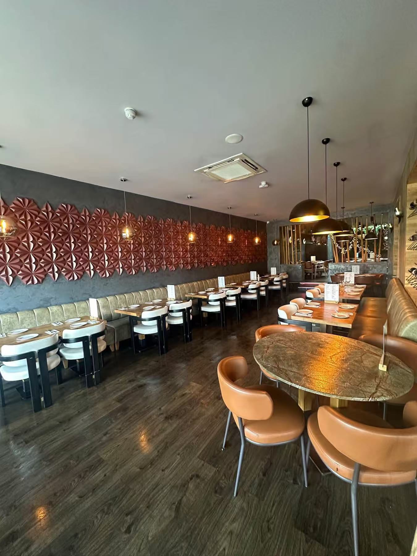 Restaurant dining room with wall banquette, round tables and warm upholstered chairs
